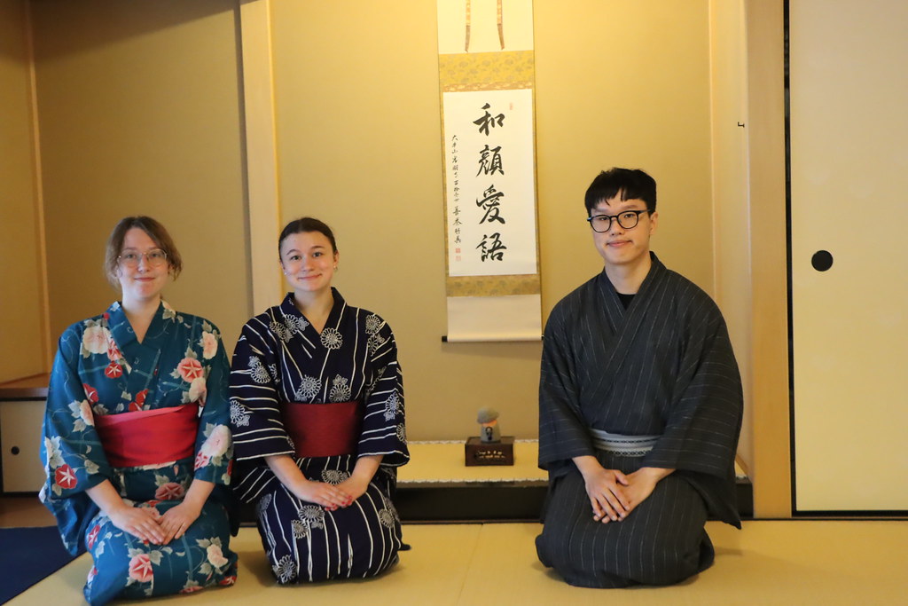 Eungi Youn, right, with two other interns. All three are sitting on a tatami mat preparing for a tea ceremony.