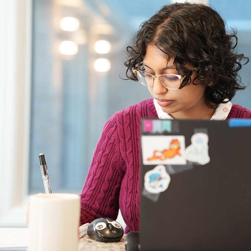 female student at home on her laptop and writing