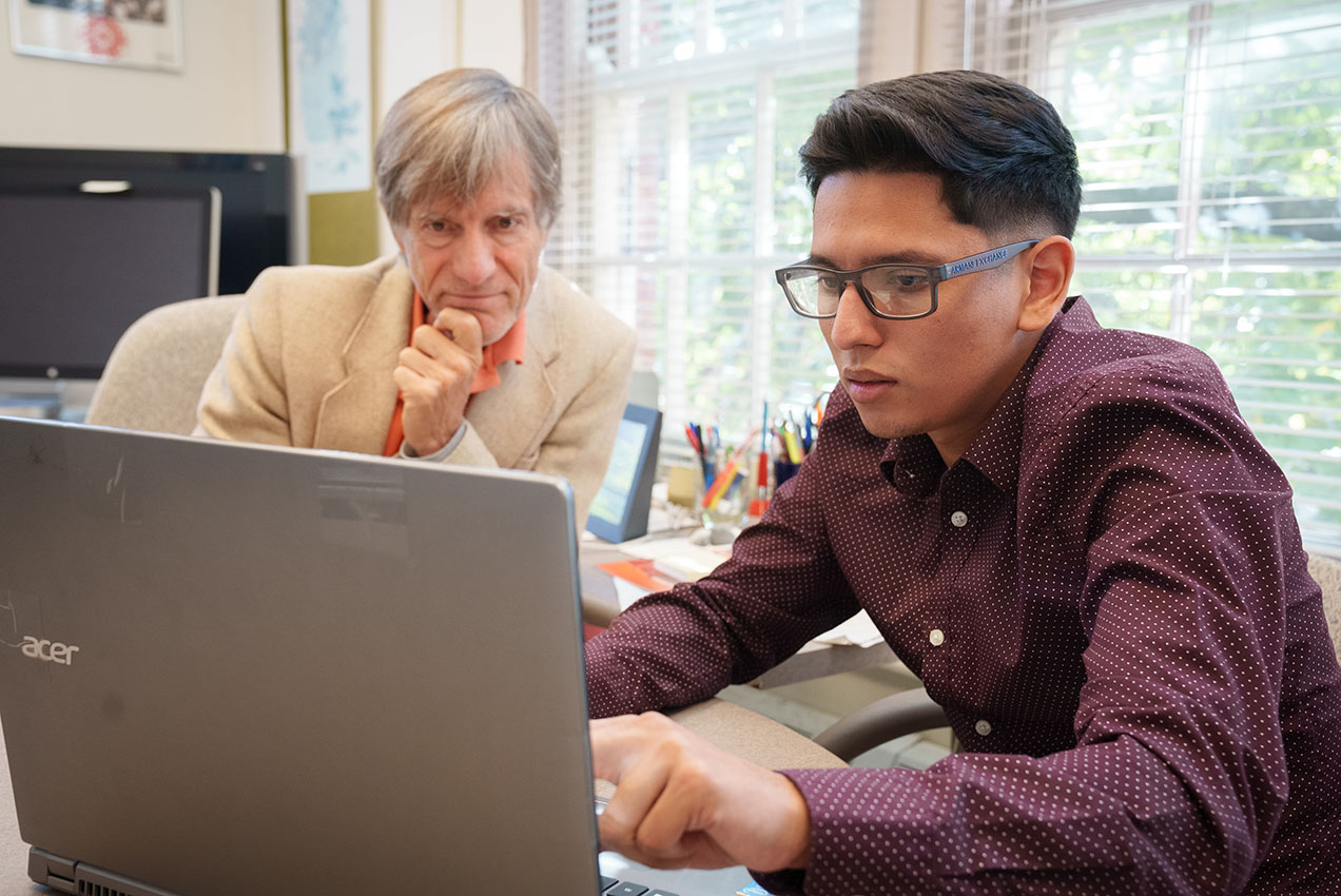 male professor looking at laptop with male student for an independent study