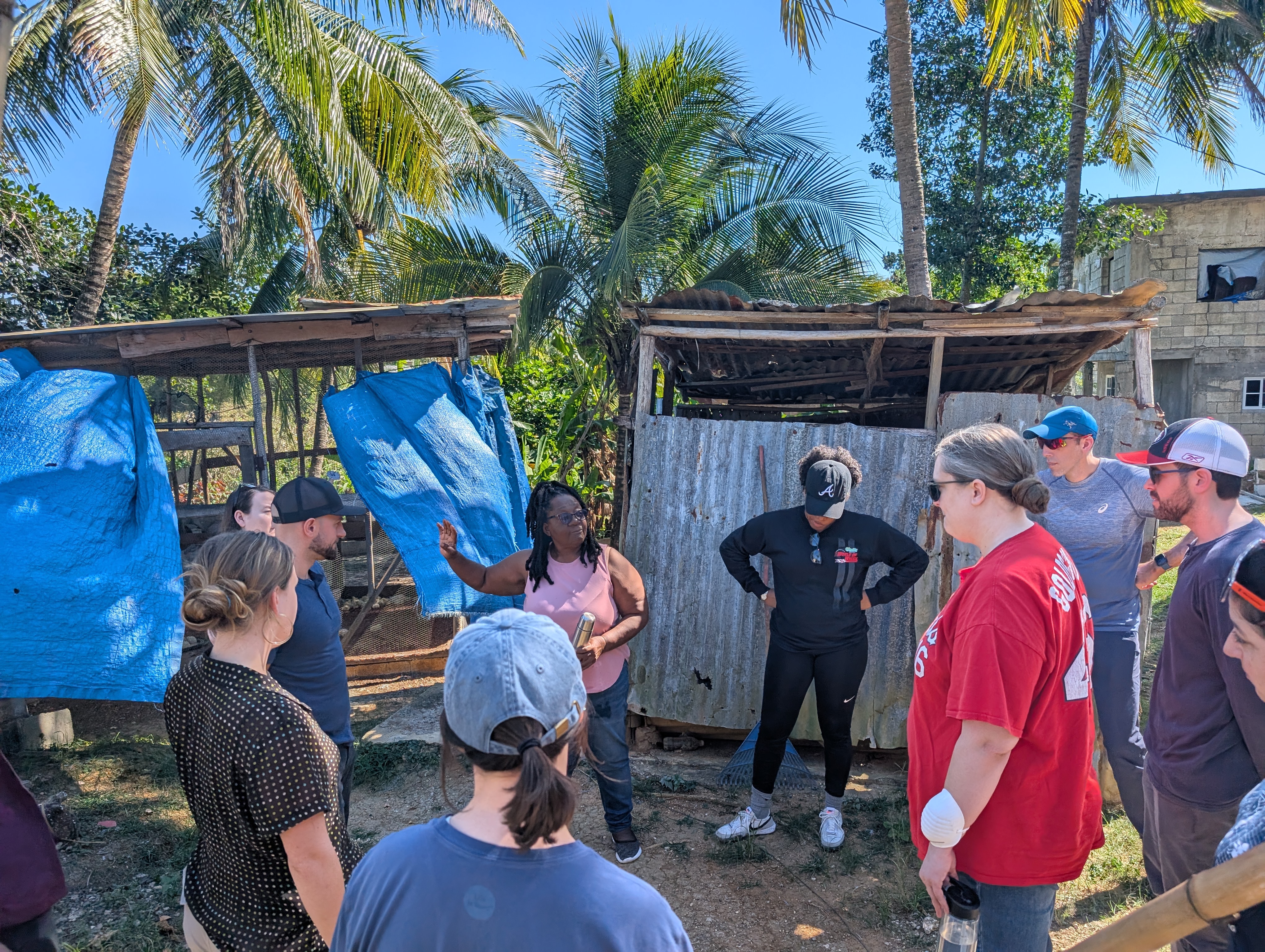 participants in front of shacks receiving instructions about their service learning project