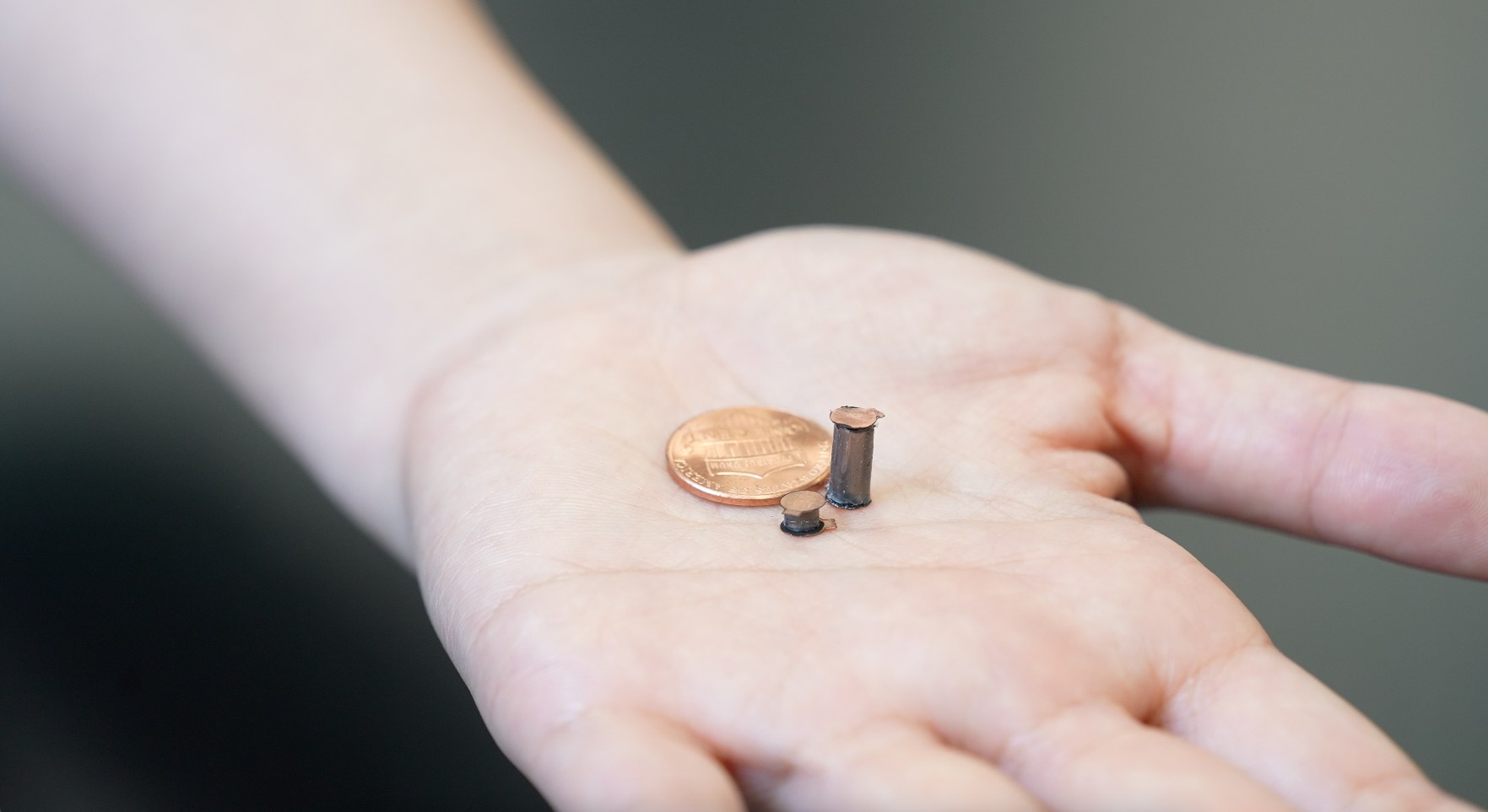 Penny sized actuators in a palm next to an actual penny to show scale.