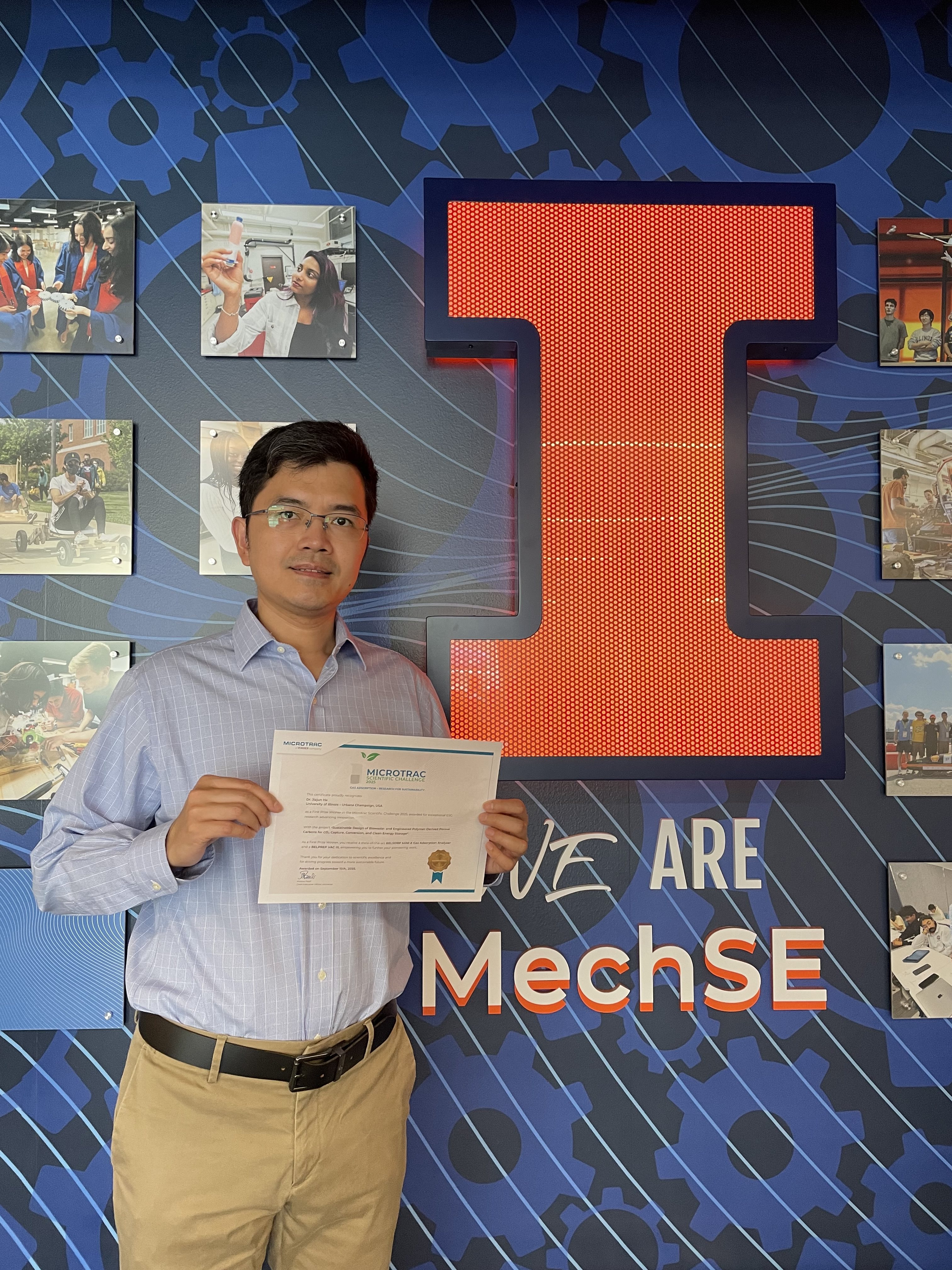 Jiajun He holding an award certificate in front of the We Are MechSE sign in Lu MEB.