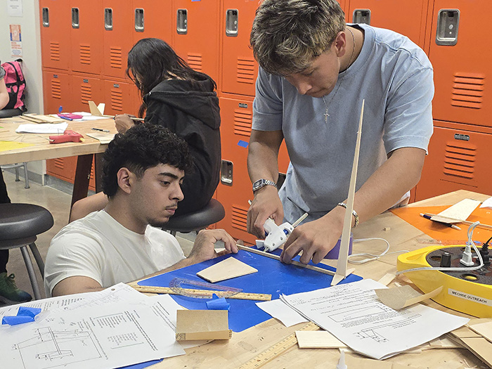 two male students working at a makerspace table on an engineering project.
