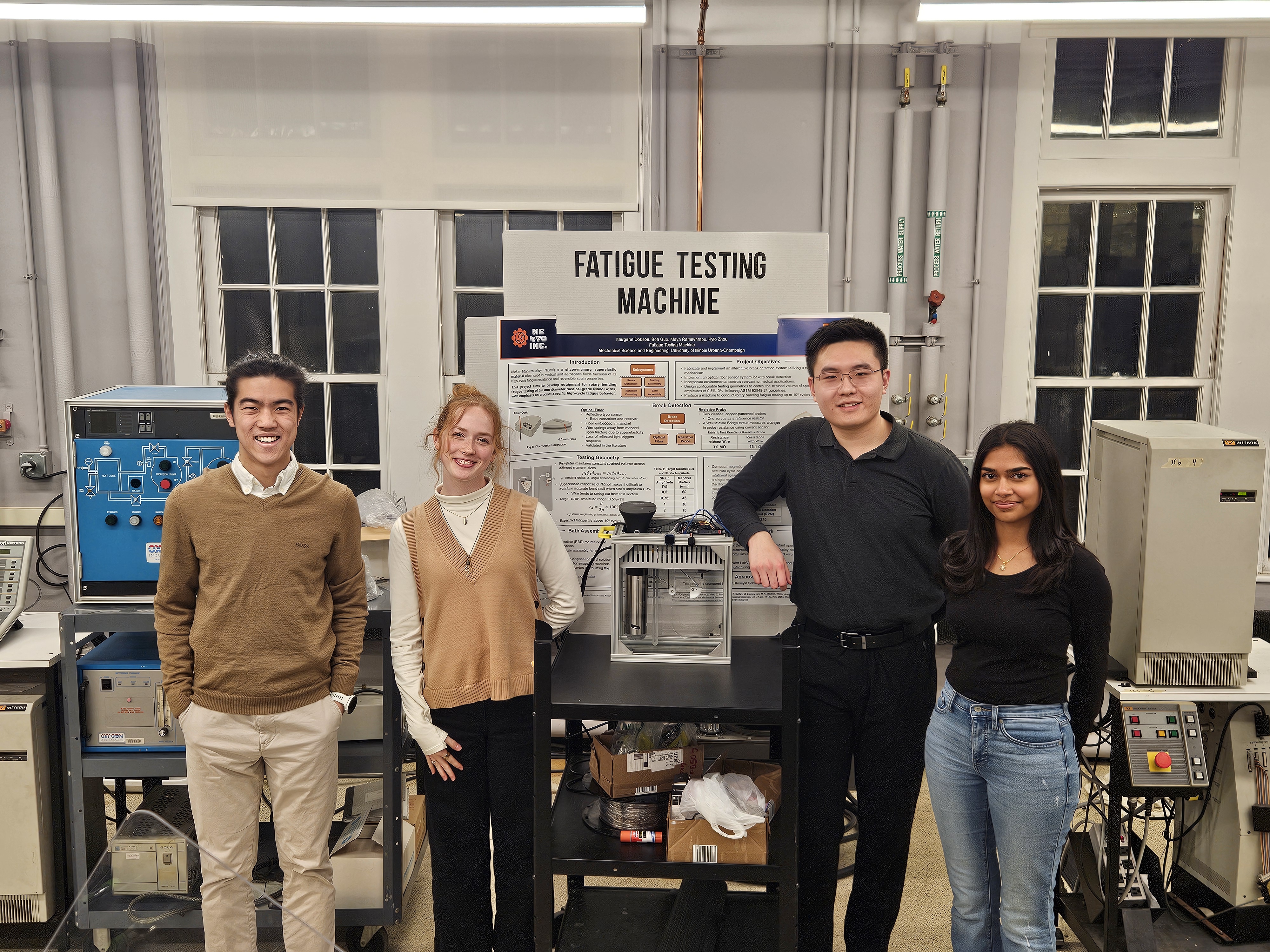 four undergraduate students standing next to the machine they designed and fabricated to test the nitinol wire