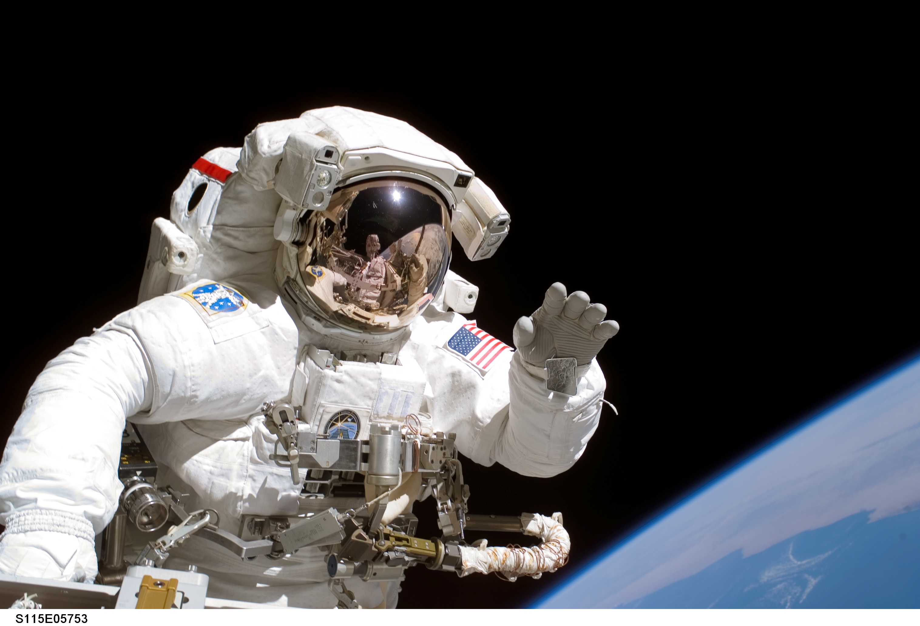 Joe Tanner waves at camera in full astronaut suit in space
