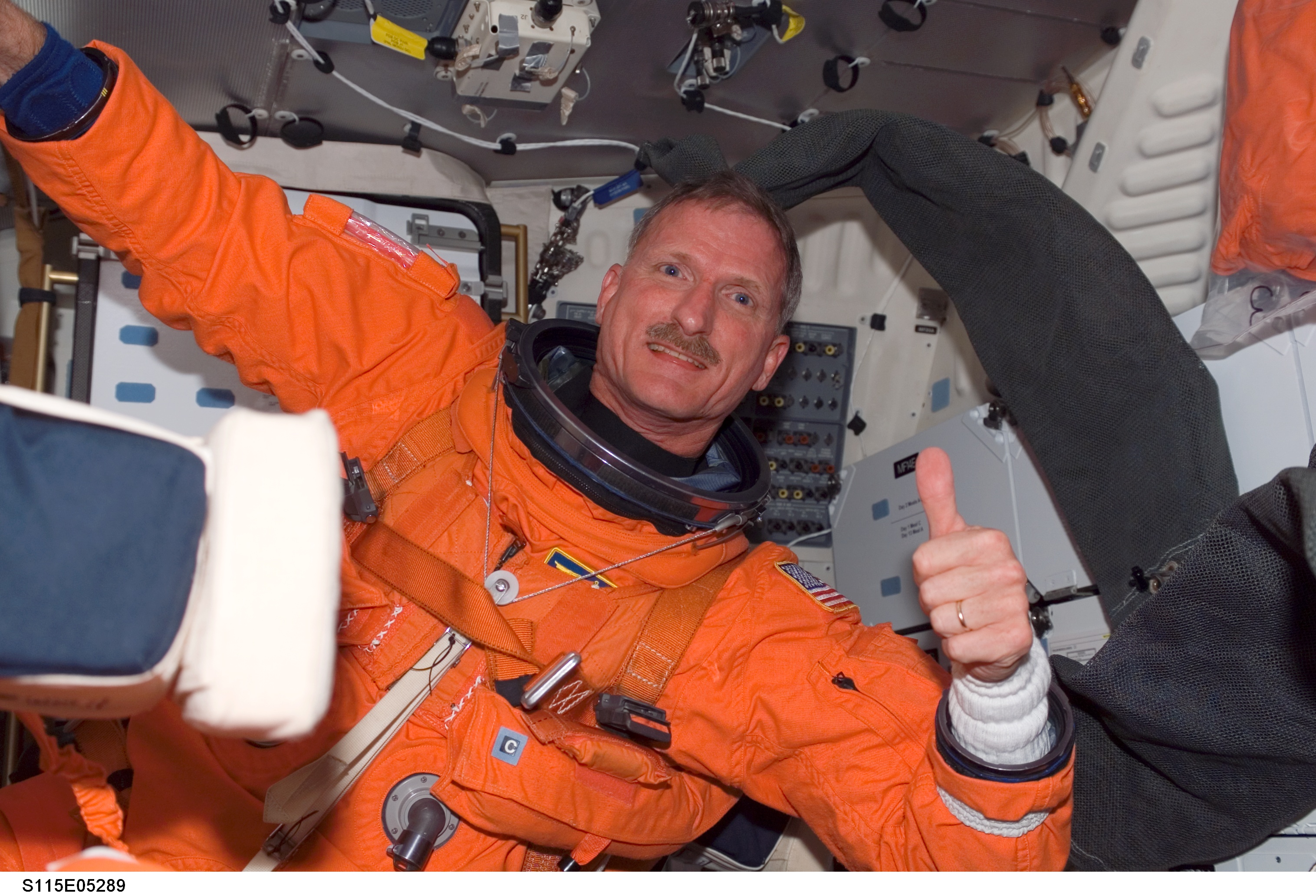 Male astronaut in orange NASA suit giving a thumbs up
