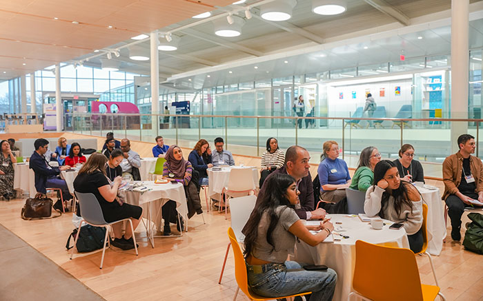 group of people sitting at small tables listening to a speaker