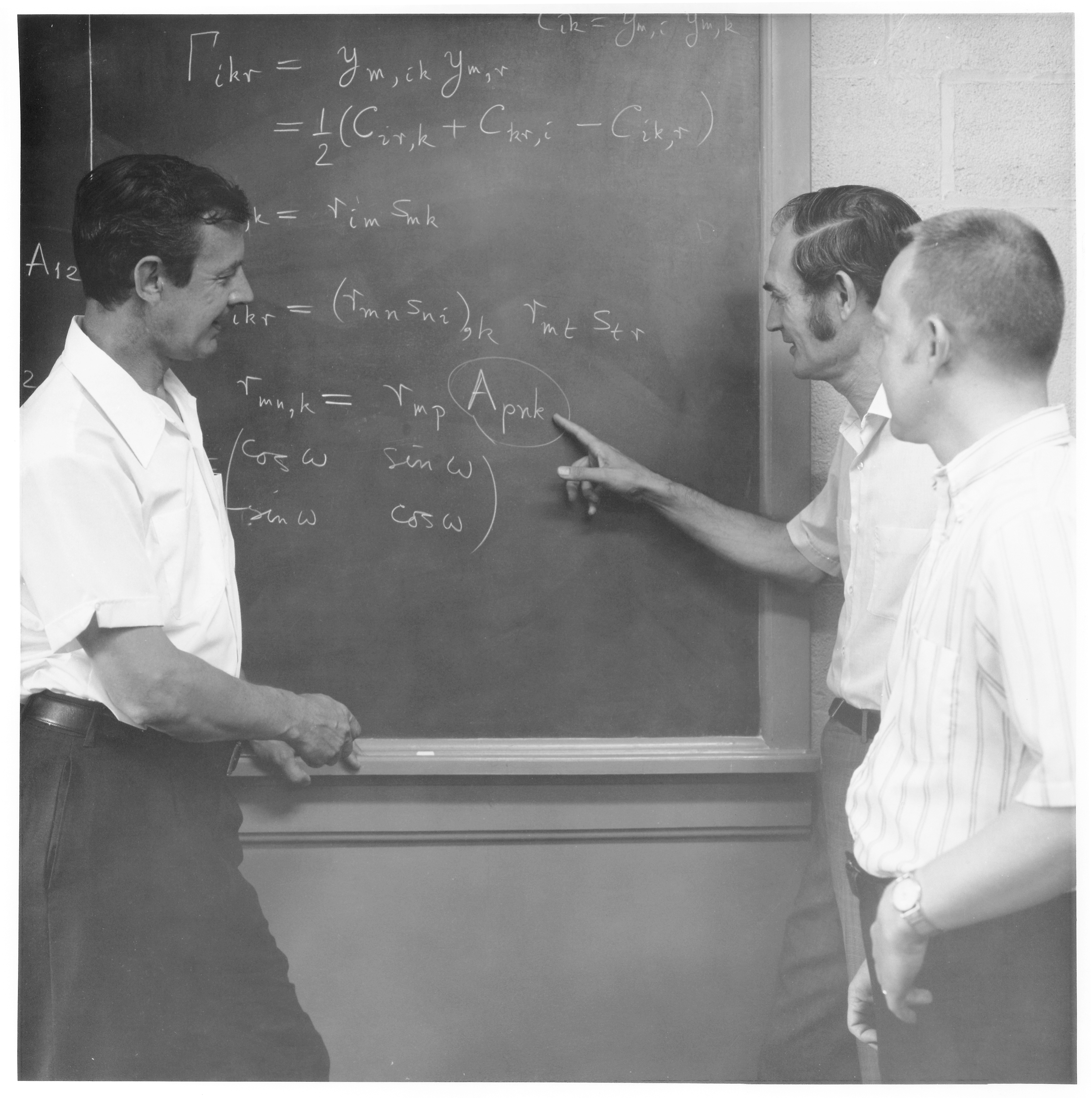 RT Shield, Marvin Stippes, and DE Carlson stand at a chalkboard, circa 1970.