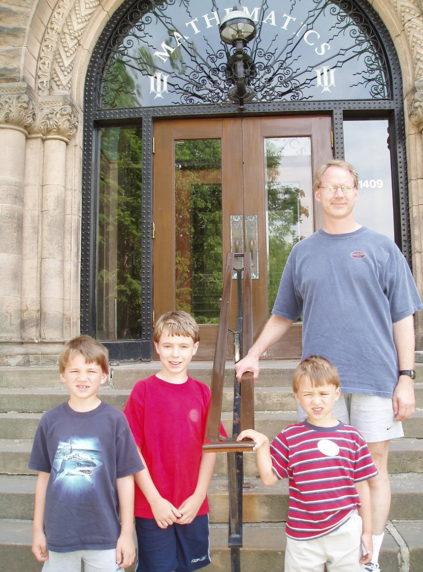 Ryan, Kevin, and Alan Wandke with their dad Norman Wandke on the steps of the Mathematics building at the University of Illinois