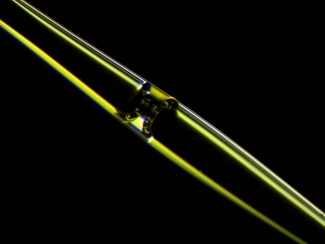 Photograph of a fluid meniscus inside an opto-mechano-fluidic resonator (OMFR) made of high purity silica glass. Particles flowing through the internal microchannel can be detected optically at extremely high speed.