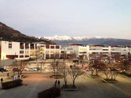View from Wagoner Johnsonâ€™s office building. The large white building across the plaza is the International School where their daughter attended school. The famous Grenoble fortress, La Bastille, can be seen on the hill behind the school, in the foreground of the snowy Chartreuse mountain range.  