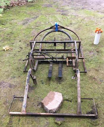 The golf cart begins with a simple frame, shown here with cables and one suspension spring attached.