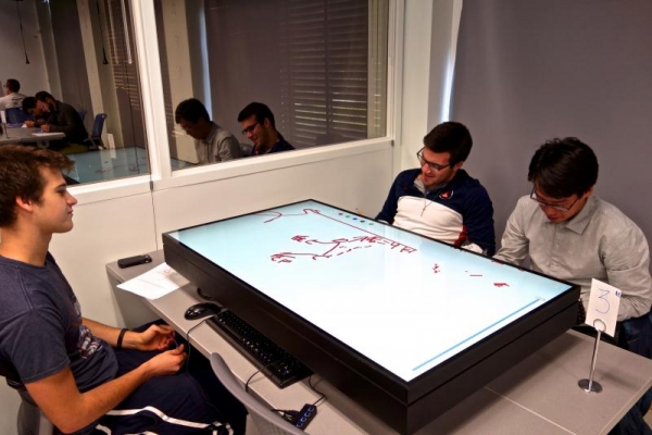 TAM 210 students using a multi-touch table during discussion.