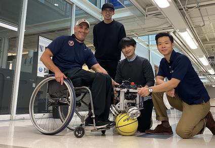 From left, University of Illinois wheelchair track team coach Adam Bleakney and graduate student researchers Chenzhang Xiao, Yu Chen and Seung Yun Song are shown Friday with the ballbot that will be used to drive their new PURE wheelchair at the Mechanical Engineering Laboratory. Photo by Chenzhang Xiao.