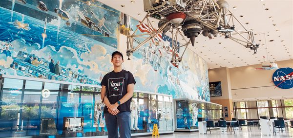 Justin stands in front of the famous JSC mural, with the only remaining lunar landing research vehicle hanging from the ceiling.