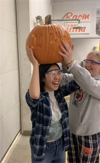Lexi and Maddie laugh with a pumpkin on Maddie's head.
