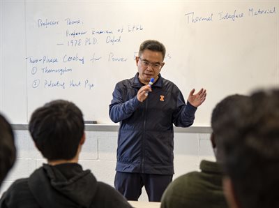 Winston Zhang teaching in front of a white board with writing.