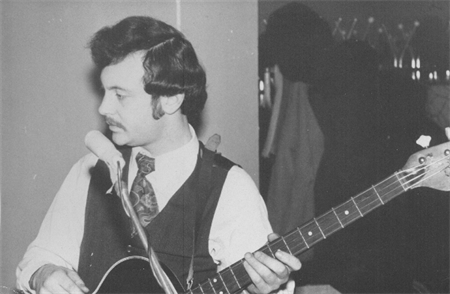 Joseph Bentsman playing guitar and singing. Black and white photo from the 1970s.