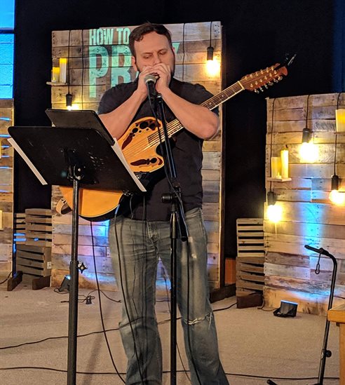 Blake Johnson in church playing the harmonica and guitar.