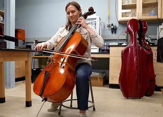 Betsy Smith playing the cello in a research lab.