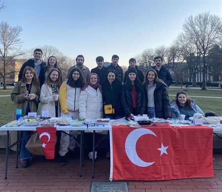 large group of students behind a table with the Turkish flas