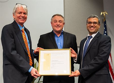 Tony Jacobi, Thomas Kenny, and Gaurav Bahl hold a framed certificate.