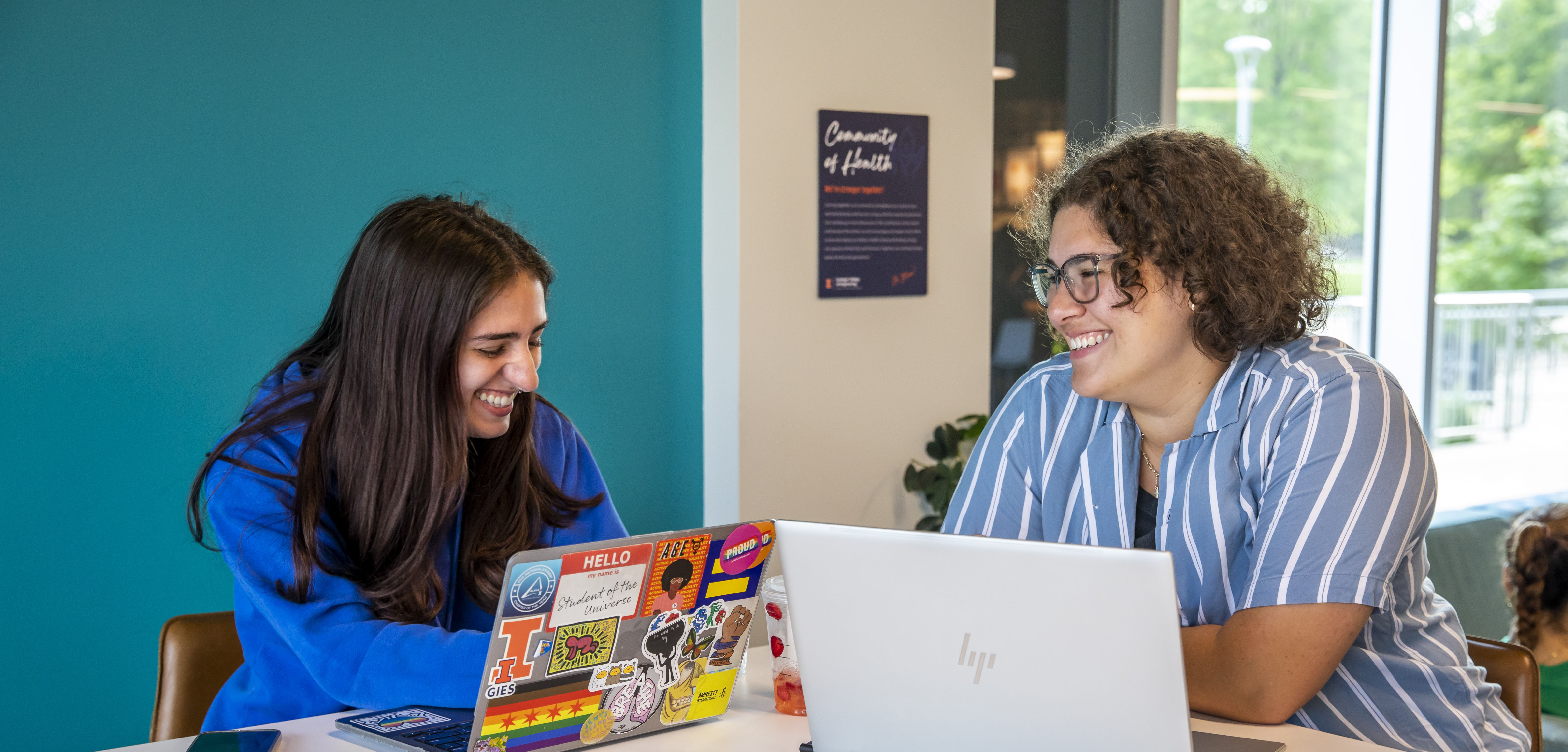 two girls talking to each other while sitting at a table.