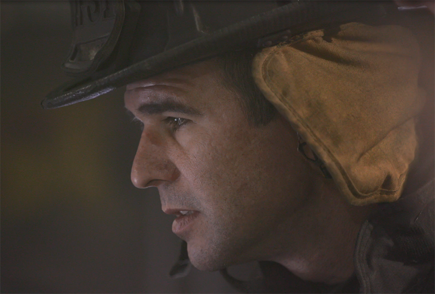 man wearing a firefighter hat looking away from camera