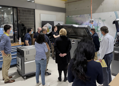 researchers stand around a large piece of equipment in a lab.