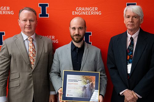 MechSE Alumni Board President Mark Woodmansee (left) and Department Head Tony Jacobi (right) present the award to Venanzio Cichella, center, holding framed certificate.