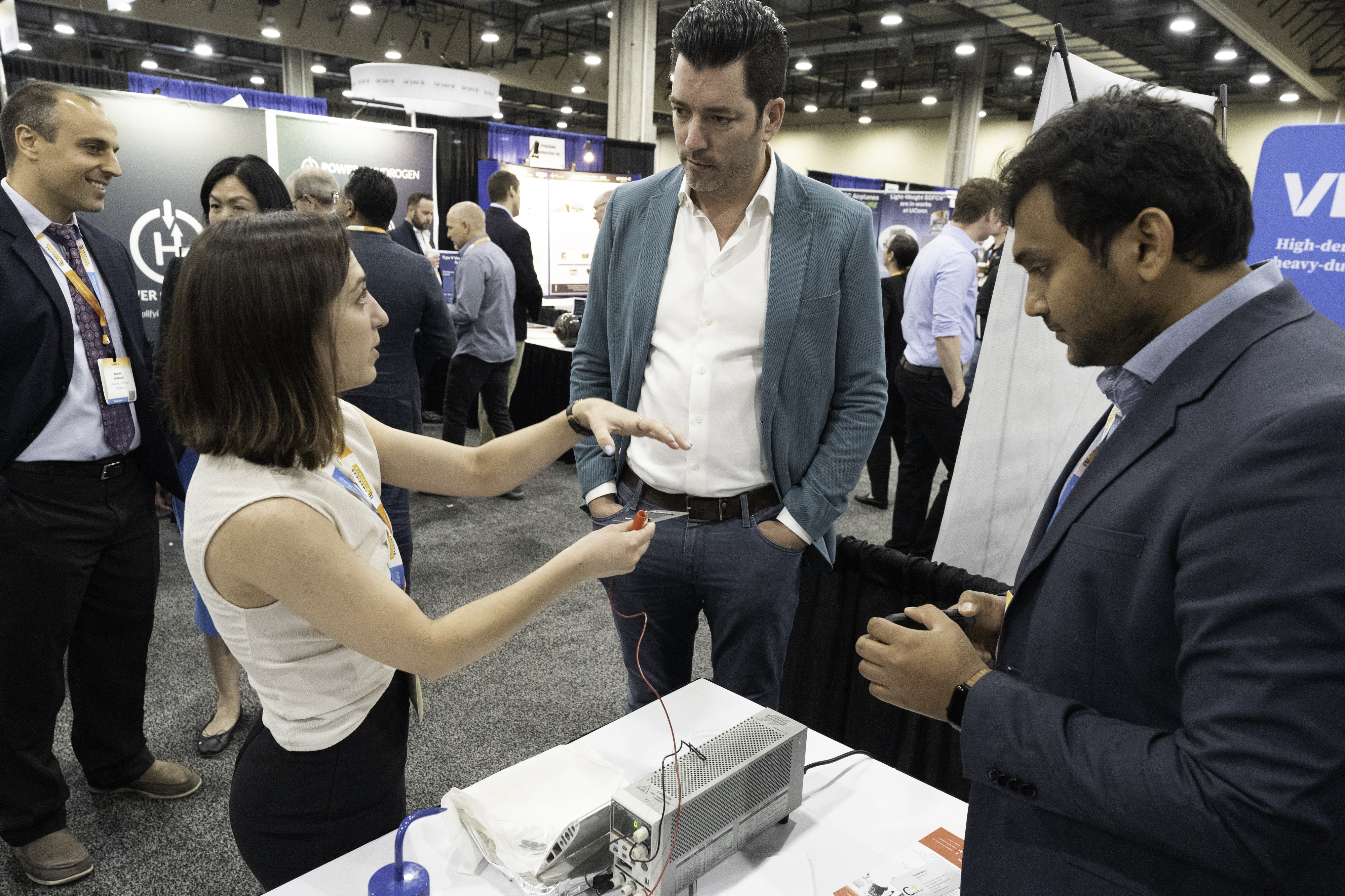 Student describing research to others at a booth in an exhibit hall.